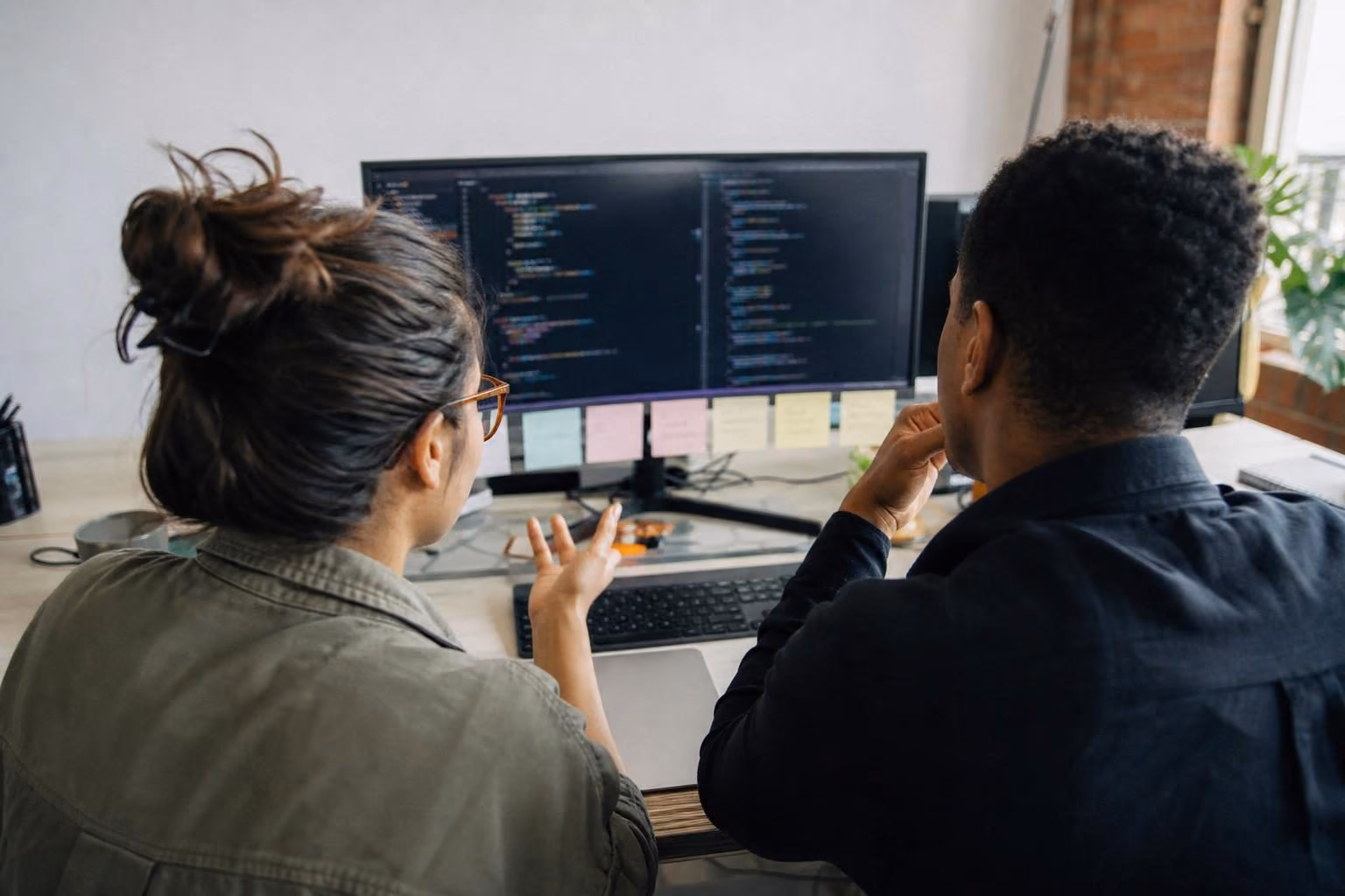 Two developers pair programming at a shared desk