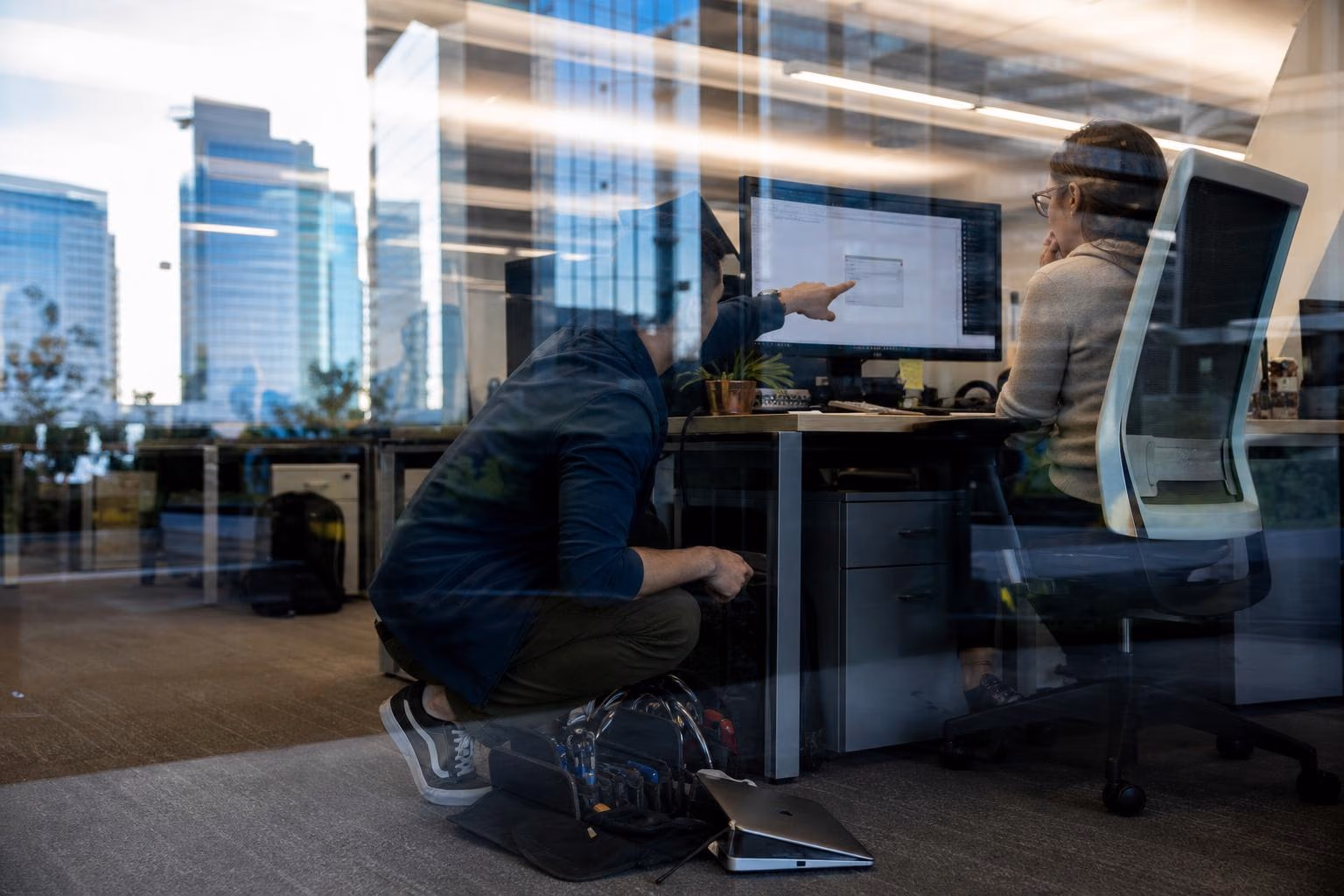 IT technician helping a colleague at her desk, in Century City